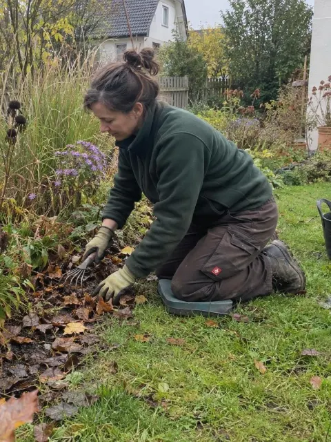 Illustration: Gärtnerin pflegt ein Staudenbeet im Herbst